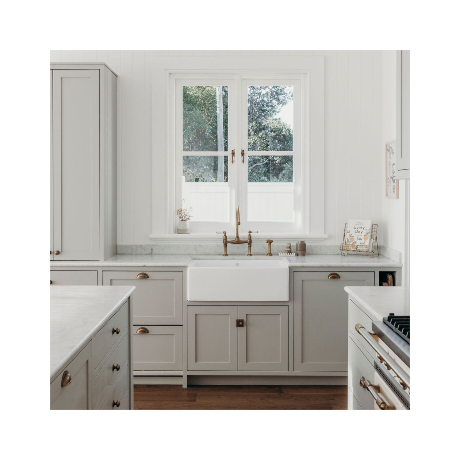 White butler’s pantry with shaker cabinetry, open shelves, fireclay farmhouse sink, chrome tapware, white subway tiles, and timber herringbone flooring in a classic home.