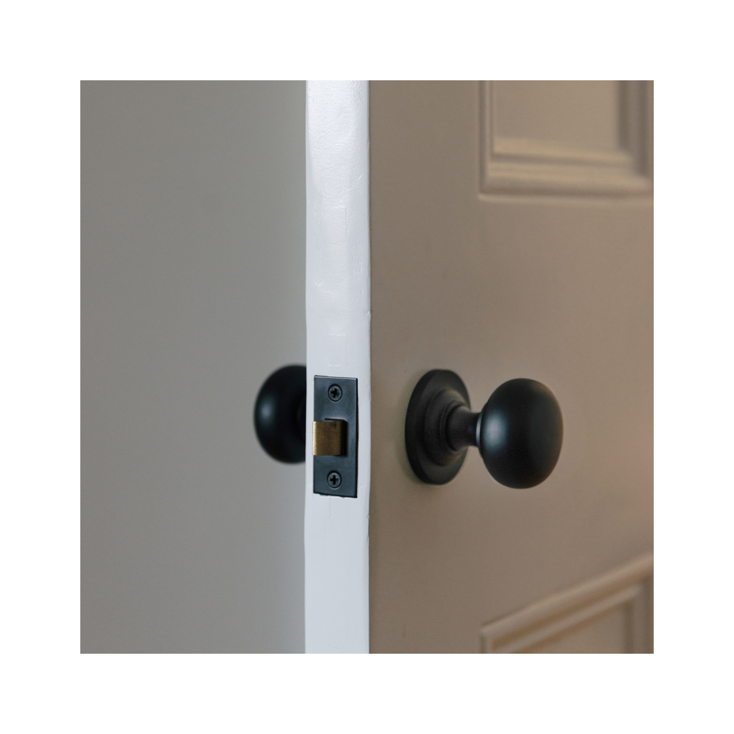 Matte black door knob on a round rose fitted to a painted traditional Victorian 4 panel door, shown with matching tube latch detail.