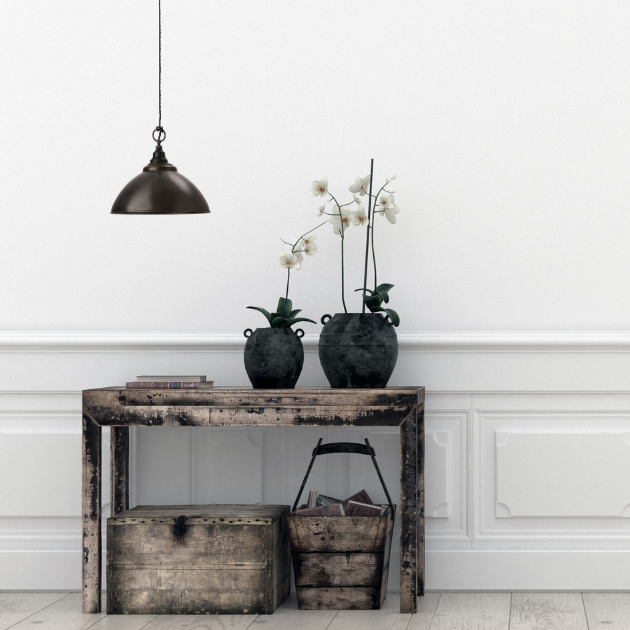 Antique bronze pendant hanging over vintage console table with decorative items against a white panelled wall